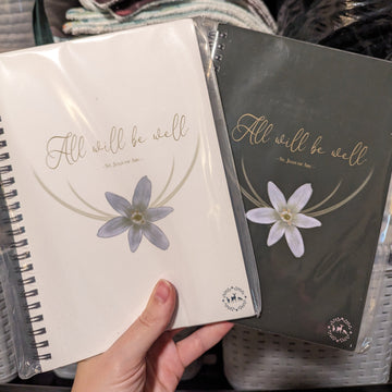 Two Catholic journals featuring St. Joan of Arc's "All Will Be Well" quote and a Star of Bethlehem flower