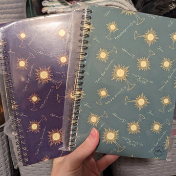 Two Catholic journals with monstrances and words from Benediction on them, one is purple and the other is teal