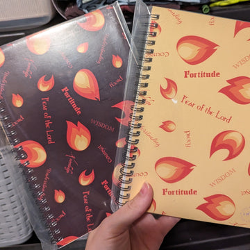 Two Catholic journals with the Gifts of the Holy Spirit design, one in brown and one in yellow with the gifts of the Holy Spirit listed along with illustrated flames.