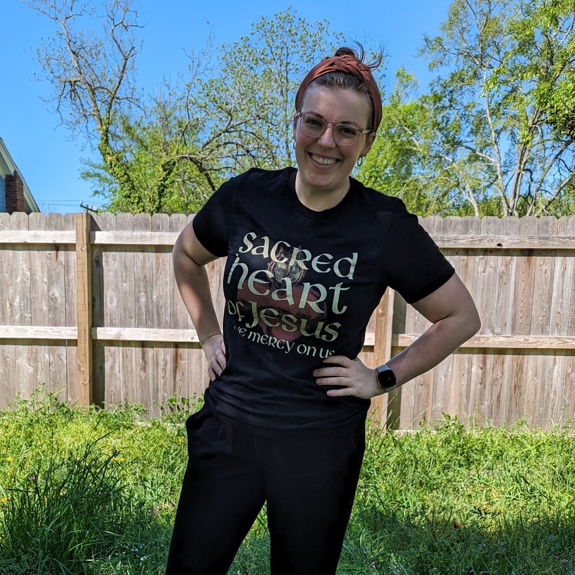 A woman wearing a black shirt that reads Sacred Heart of Jesus Have Mercy on Us