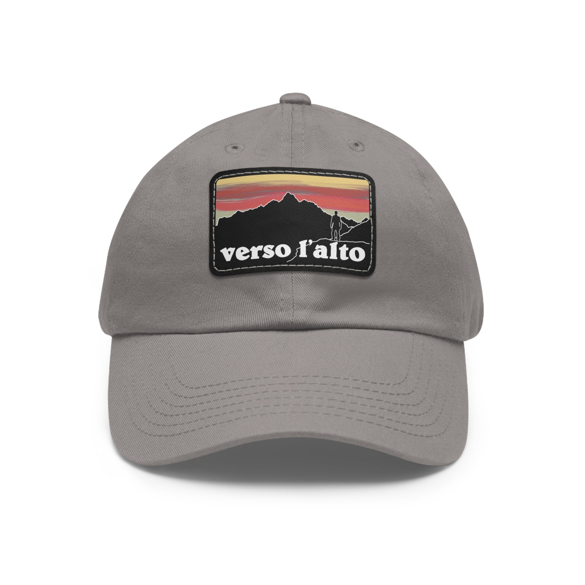 Gray cap with a mountainous sunset image and text reading verso lalto. A mountaineer stands atop a ridge symbolizing Pier Giorgio Frassati.